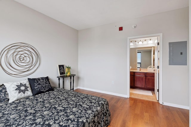 bedroom with electric panel, ensuite bath, and light hardwood / wood-style floors