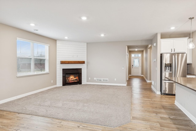 unfurnished living room featuring a fireplace and light hardwood / wood-style flooring