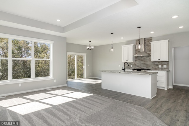 kitchen featuring tasteful backsplash, wall chimney range hood, dark hardwood / wood-style floors, white cabinetry, and hanging light fixtures