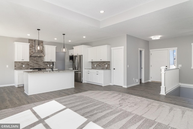 kitchen featuring wall chimney exhaust hood, dark hardwood / wood-style flooring, an island with sink, and appliances with stainless steel finishes