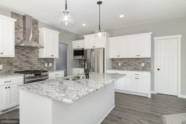 kitchen with a center island with sink, wall chimney range hood, hanging light fixtures, dark hardwood / wood-style flooring, and stainless steel appliances