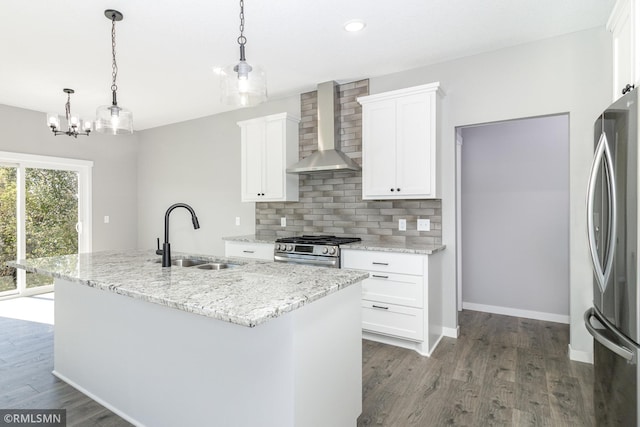 kitchen featuring white cabinetry, sink, stainless steel appliances, wall chimney range hood, and an island with sink