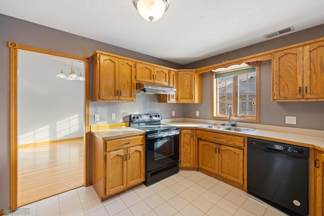 kitchen with a textured ceiling, sink, black appliances, light hardwood / wood-style flooring, and hanging light fixtures