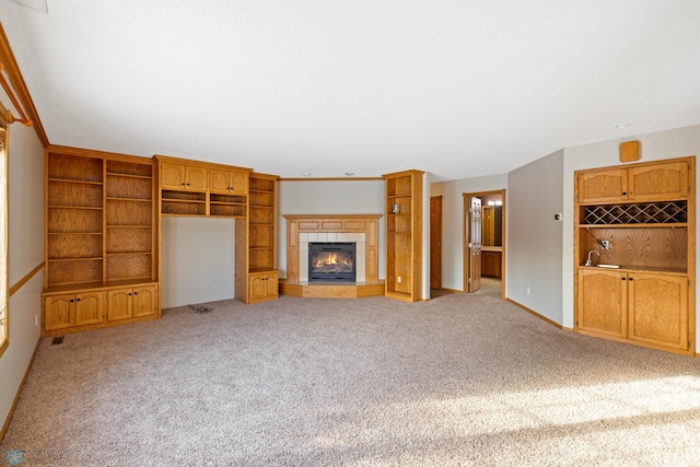 unfurnished living room with light carpet, a fireplace, and crown molding