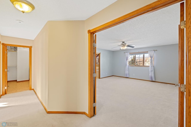 hall featuring a textured ceiling and light carpet