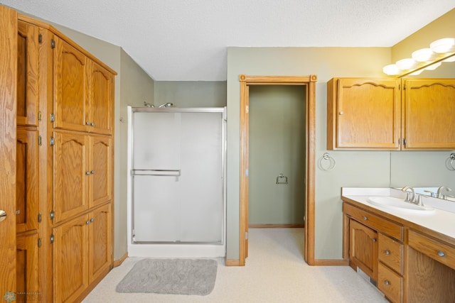 bathroom featuring vanity, a textured ceiling, and a shower with door