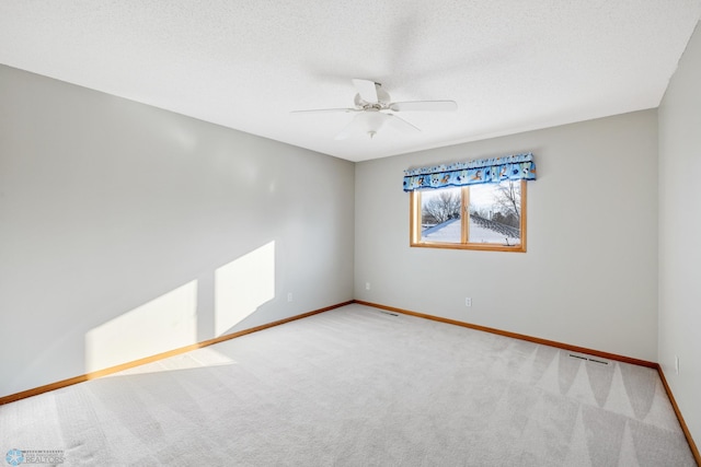 carpeted empty room with ceiling fan and a textured ceiling