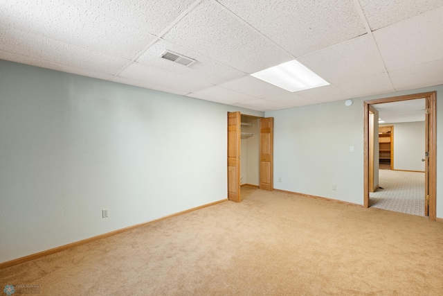 carpeted empty room featuring a drop ceiling