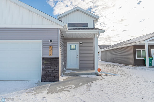 snow covered property entrance featuring a garage