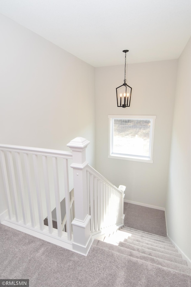 stairway with carpet flooring and a chandelier