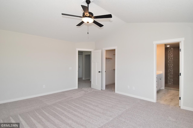 unfurnished bedroom with ceiling fan, ensuite bathroom, light colored carpet, a walk in closet, and a closet