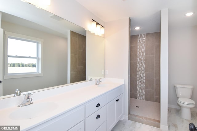 bathroom featuring vanity, toilet, and a tile shower