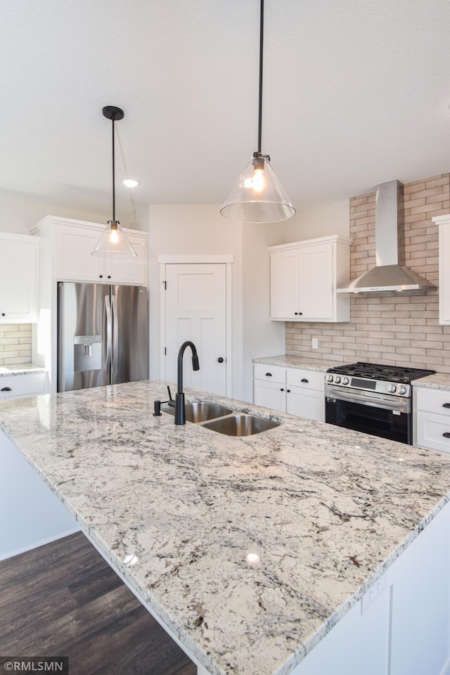 kitchen with decorative light fixtures, white cabinets, stainless steel appliances, and wall chimney range hood