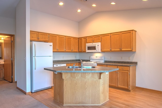 kitchen featuring a kitchen bar, a center island with sink, white appliances, and sink