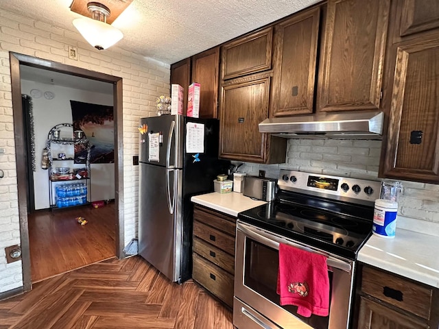 kitchen with brick wall, dark parquet flooring, dark brown cabinetry, and appliances with stainless steel finishes