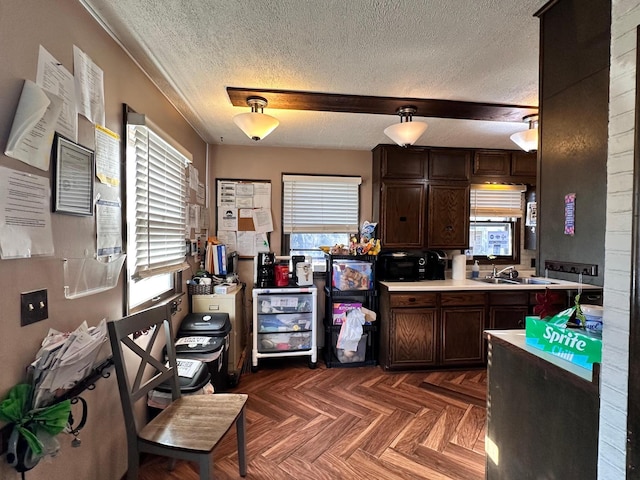 kitchen featuring a textured ceiling, dark brown cabinetry, plenty of natural light, and sink