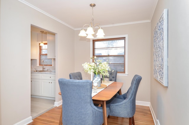 dining area featuring light wood-type flooring, crown molding, and a notable chandelier