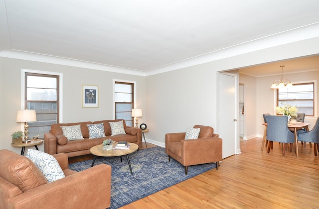 living room featuring wood-type flooring, crown molding, and a chandelier