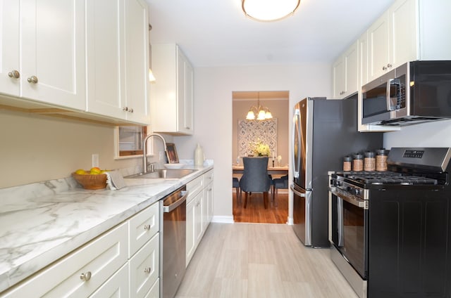 kitchen featuring white cabinets, pendant lighting, stainless steel appliances, and light hardwood / wood-style floors