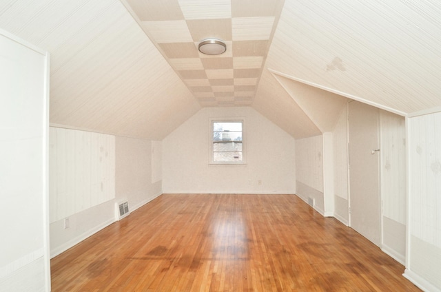 additional living space with hardwood / wood-style flooring and vaulted ceiling