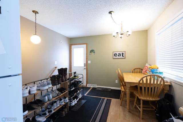 dining space with hardwood / wood-style floors, a chandelier, and a textured ceiling