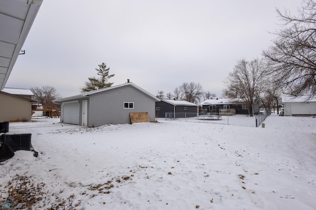 snow covered house featuring a garage and an outdoor structure