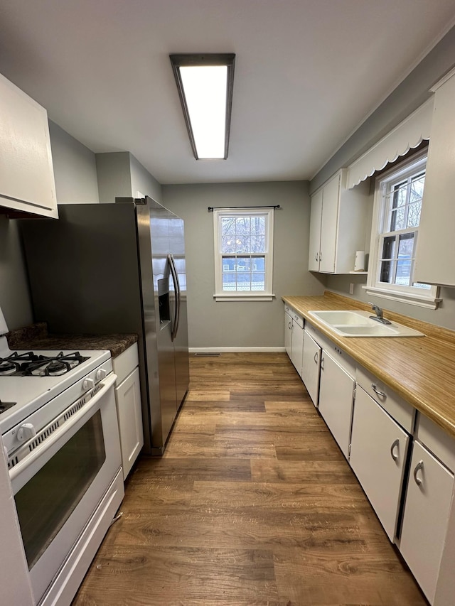 kitchen featuring white cabinets, plenty of natural light, and white range with gas stovetop