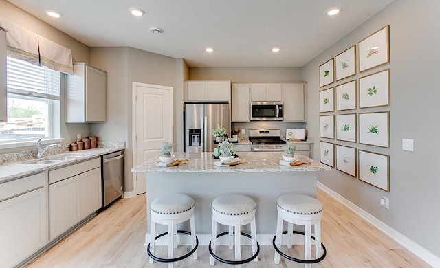 kitchen featuring white cabinets, sink, light hardwood / wood-style floors, appliances with stainless steel finishes, and a kitchen island