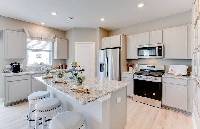 kitchen with white cabinets, a center island, light hardwood / wood-style floors, and stainless steel appliances