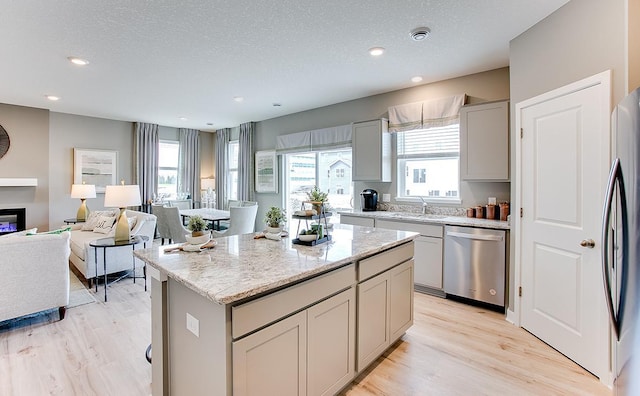 kitchen with appliances with stainless steel finishes, a center island, a textured ceiling, and a healthy amount of sunlight