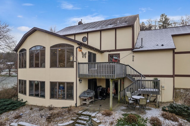 snow covered back of property with a patio area