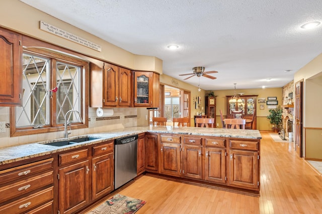 kitchen with kitchen peninsula, a textured ceiling, sink, dishwasher, and light hardwood / wood-style floors