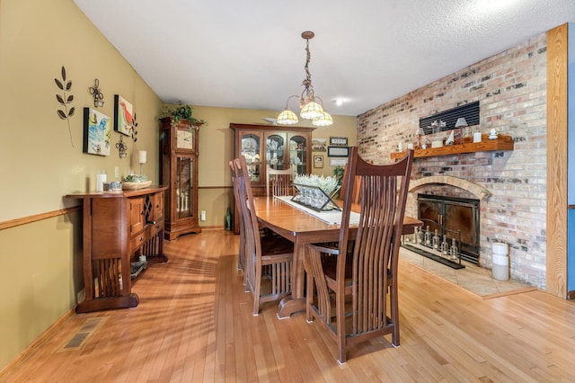 dining space featuring a chandelier, light hardwood / wood-style flooring, and a fireplace