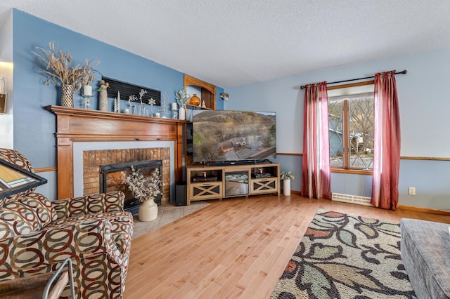 living room with hardwood / wood-style floors, a fireplace, a textured ceiling, and a baseboard radiator