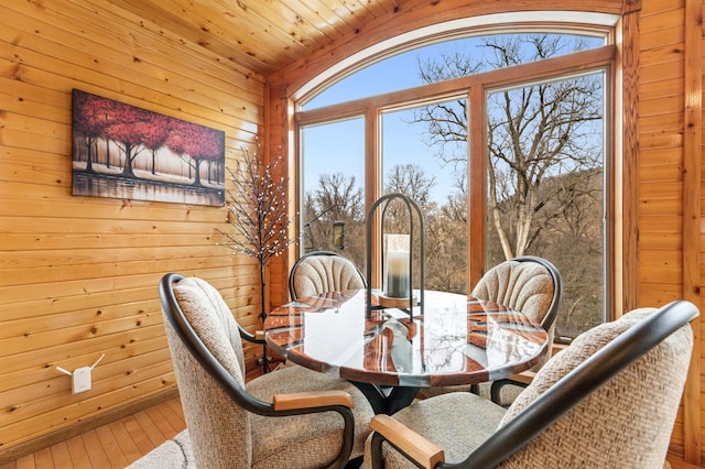 dining area featuring vaulted ceiling, wood walls, wood-type flooring, and wooden ceiling