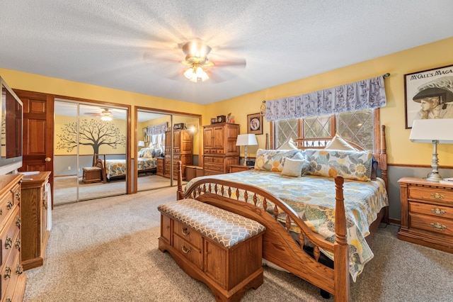 bedroom featuring multiple closets, ceiling fan, light colored carpet, and a textured ceiling