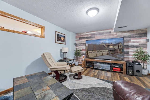 living room with wood-type flooring, a textured ceiling, and wooden walls