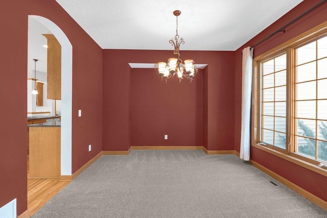 empty room with light carpet and a notable chandelier