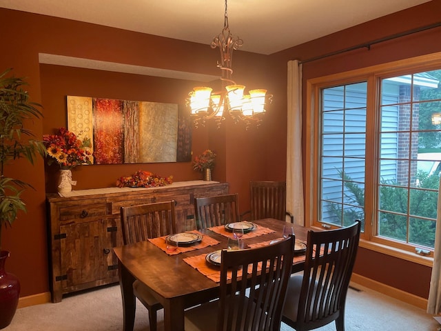 dining room with a healthy amount of sunlight, light colored carpet, and a chandelier