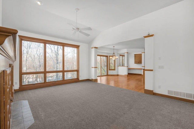 unfurnished living room with carpet flooring, ceiling fan with notable chandelier, a fireplace, and vaulted ceiling