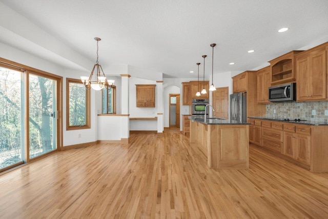 kitchen featuring plenty of natural light, an island with sink, hanging light fixtures, and appliances with stainless steel finishes