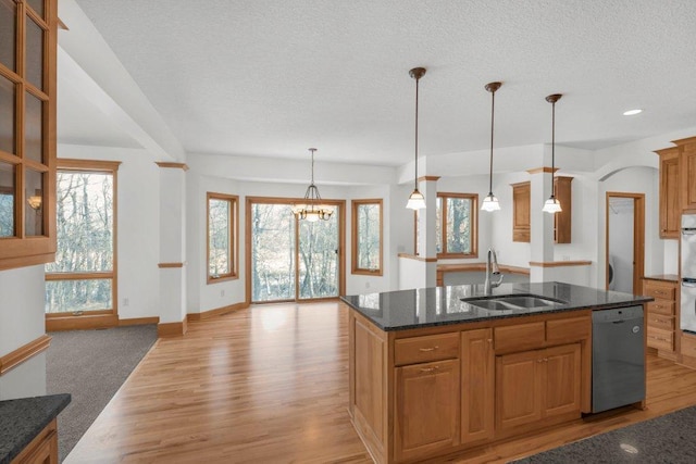 kitchen with dishwasher, light hardwood / wood-style flooring, hanging light fixtures, and an island with sink