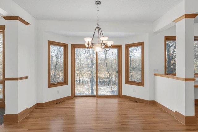 unfurnished dining area with an inviting chandelier and light wood-type flooring