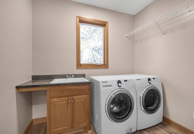 laundry area featuring cabinets, light wood-type flooring, sink, and washing machine and clothes dryer