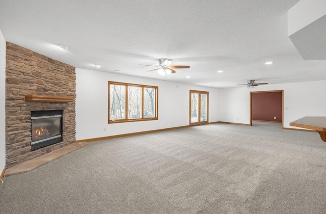 unfurnished living room featuring ceiling fan, a fireplace, carpet, and a textured ceiling