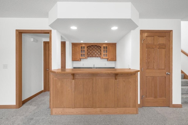 kitchen featuring a textured ceiling, kitchen peninsula, and light carpet