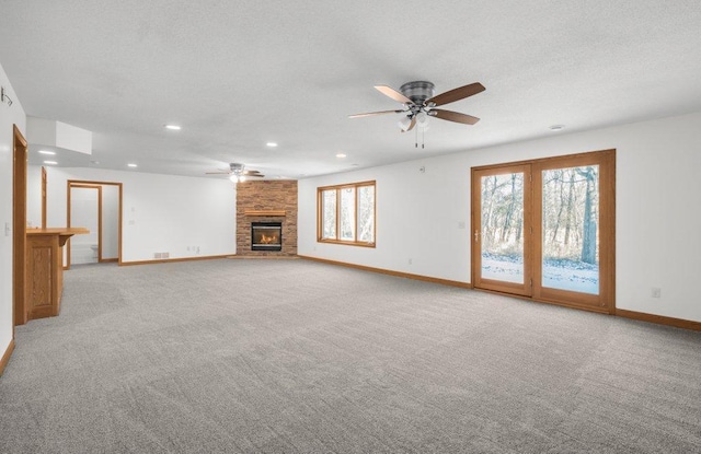 unfurnished living room featuring ceiling fan, a fireplace, and light colored carpet