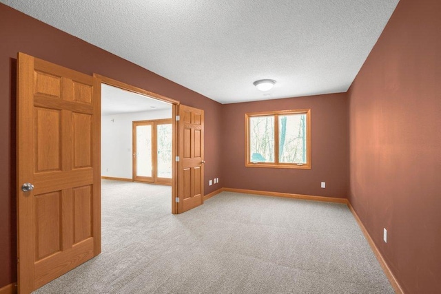 unfurnished room with light carpet, a textured ceiling, and a wealth of natural light