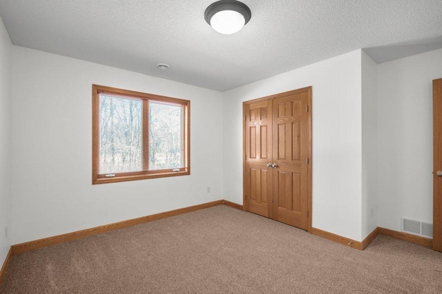 unfurnished bedroom with light carpet, a closet, and a textured ceiling