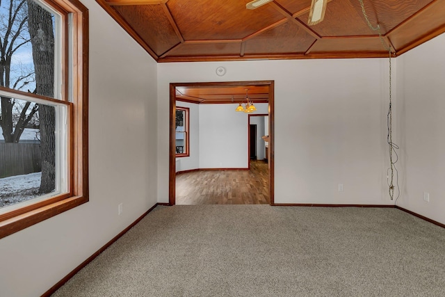 carpeted empty room with wooden ceiling, ceiling fan with notable chandelier, and ornamental molding